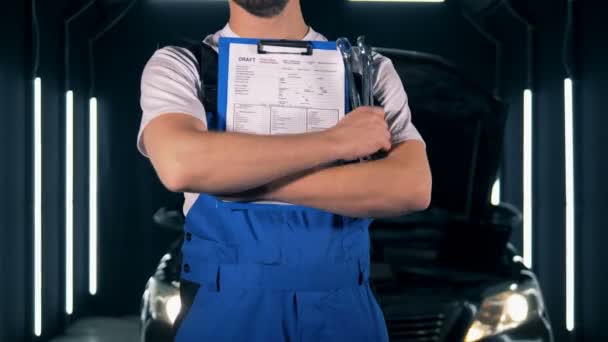 Repairman fixing a car. Car service concept. Repairman standing with a clipboard, close up. — Stock Video