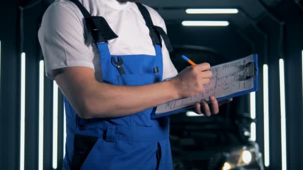 Mekaniker som skriver på ett papper på ett urklipp, närbild. — Stockvideo