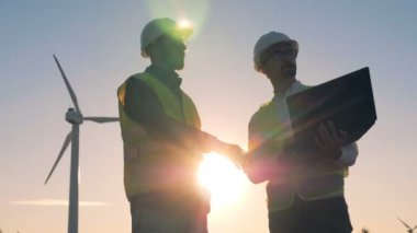 Yenilenebilir electririty, yeşil enerji kavramı. Yel değirmenleri birlikte çalışan kişiler.