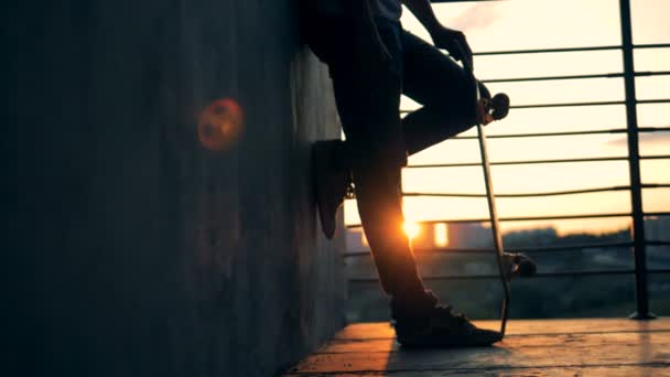 Un hombre monta un monopatín sobre un fondo al atardecer, en cámara lenta . — Vídeos de Stock