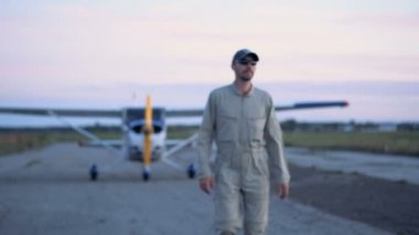 Erkek pilot bir çift kanatlı uzak yürüyor ve bir gülümseme ile durur