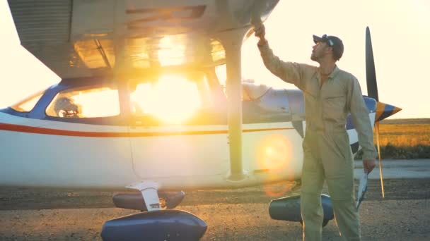 Mannelijke piloot is het reinigen van een vliegtuig tijdens zonsondergang — Stockvideo