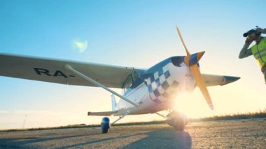 Neşeli erkek havacı geliyor ve bir uçak ayakta