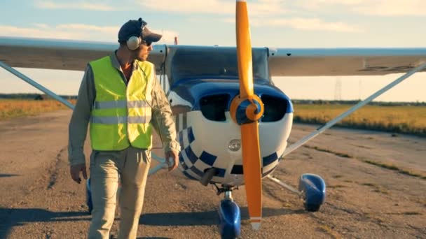 Male aviator walks away from the plane and taking off the headphones — Stock Video