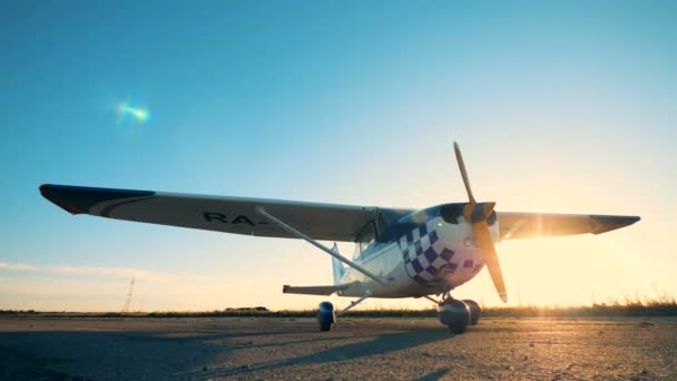 Un pequeño avión está parado en una pista de despegue en un campo abierto — Vídeos de Stock