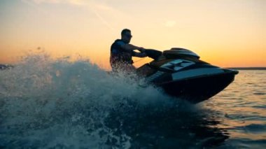 Yetişkin bir adam bir waverunner sürüş ile günbatımı waterscape