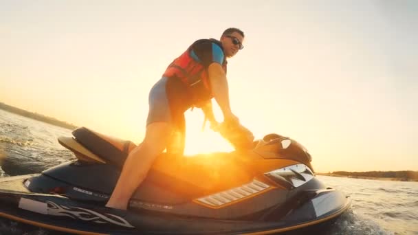 Motorista iluminado do sol de uma scooter de água que atravessa o lago — Vídeo de Stock