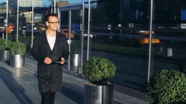 Genç işadamı elinde bir tablet ile sokak şehir boyunca yürüyor. Kızıl epik ejder 6k vurdu.