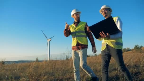 Muži mluví při kontrole větrných mlýnů, zblízka. Obnovitelné enrgy koncept. — Stock video