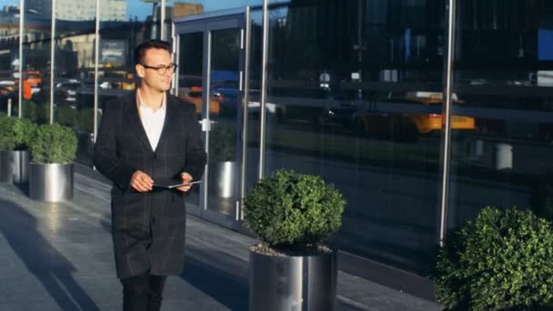 El joven empresario camina por la calle de la ciudad con una tableta en sus manos. Dragón épico rojo 6K tiro . — Vídeos de Stock