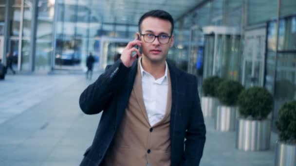 Telefonisch gesprek van een zakenman die wandelen in de stedelijke street, downtown. Rode epische film camera beelden. — Stockvideo