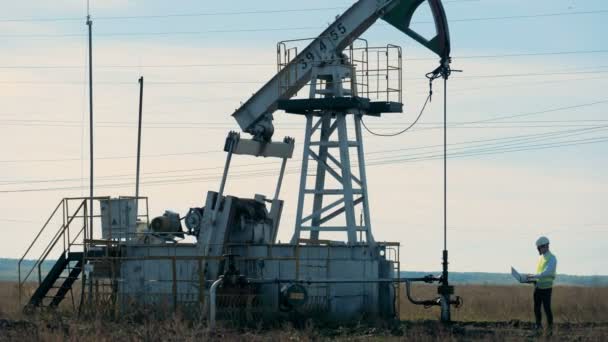 Adam bir petrol derrick, yağ pompası eserleri denetler. — Stok video