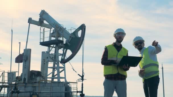 Ingenieure arbeiten auf einem Ölfeld in der Nähe von Ölpumpen zusammen. — Stockvideo