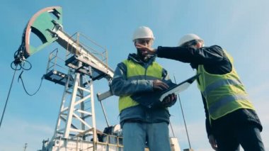 İşçiler bir petrol derrick arka plan üzerinde konuşalım. Fosil yakıt, petrol sanayi kavramı.