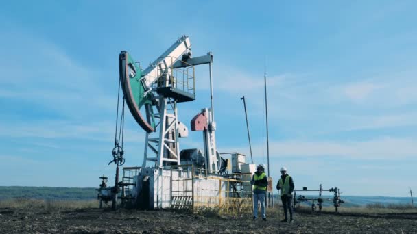 Dos hombres revisan una torre de petróleo. Combustible fósil, concepto de industria petrolera . — Vídeo de stock