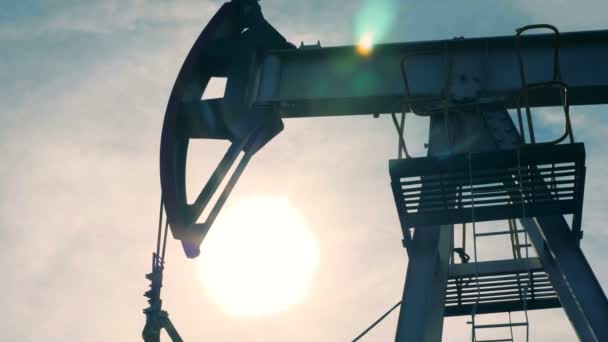 Bomba de aceite de trabajo sobre un fondo del cielo, de cerca. El equipo de bombeo funciona en un campo petrolífero . — Vídeos de Stock