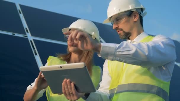 Une femme et un homme ingénieurs solaires tiennent une discussion — Video