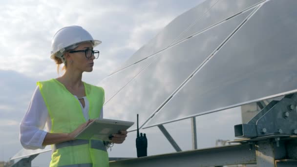 Construtora feminina está de pé perto de uma bateria solar e trabalhando com seu tablet — Vídeo de Stock