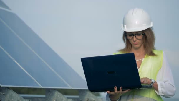 Linda senhora trabalhador está andando com seu laptop perto de uma bateria solar — Vídeo de Stock