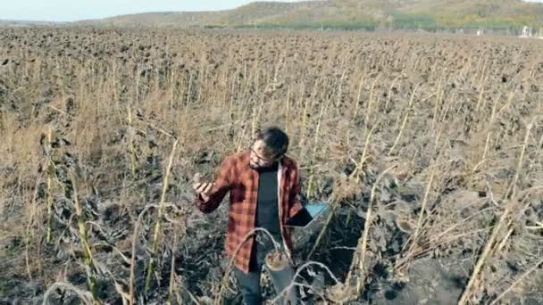 Zemědělec na poli s odumřelých rostlin stojí. Koncept poškozený plodin. — Stock video