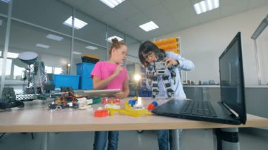 Bir kız bir laboratuvar odasında bir tablet ile çalışsa da bir çocuk bir robot giderir. Modern eğitim kavramı.