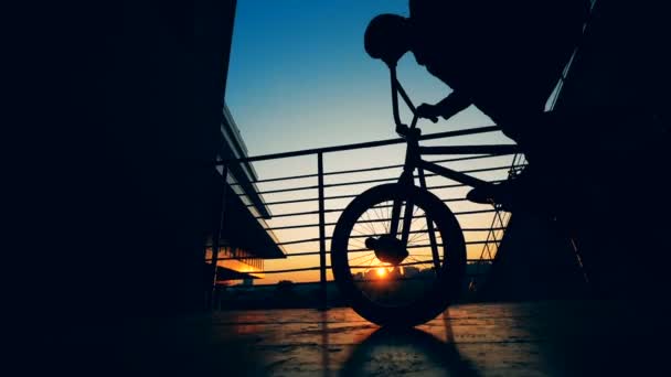 Teenager balancing on a bikes wheel on a city background, slow motion. — Stock Video