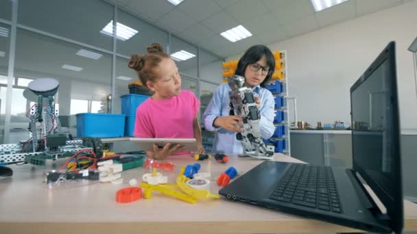 Deux écoliers construisent un robot en plastique dans un laboratoire scolaire. Concept d'enseignement technique . — Video