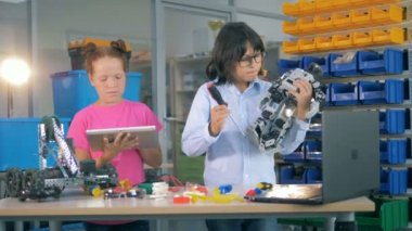 İki çocuk bir laboratuvarda bir robot sabitleme. Yenilikçi teknik eğitim kavramı.