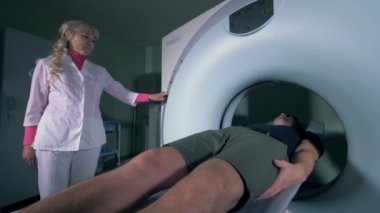 Kadın tıbbi çalışan işlemi bir MRI makinesi dışında hareketli hastaların kontrol ediyor