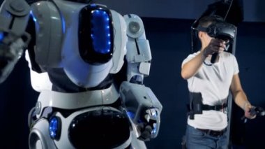 Bir adam bir robot bir sanal gerçeklik kümesiyle maniple ediyor. Sanal gerçeklik oyun kavramı.