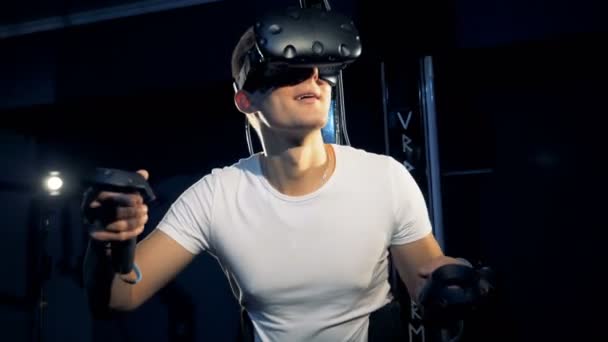 Virtual reality platform is being used by a young man in gaming process. Virtual reality gaming concept. — Stock Video