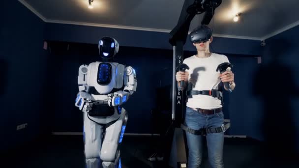 Robô humano e um adolescente em óculos de realidade virtual estão jogando as mãos para a frente juntos — Vídeo de Stock