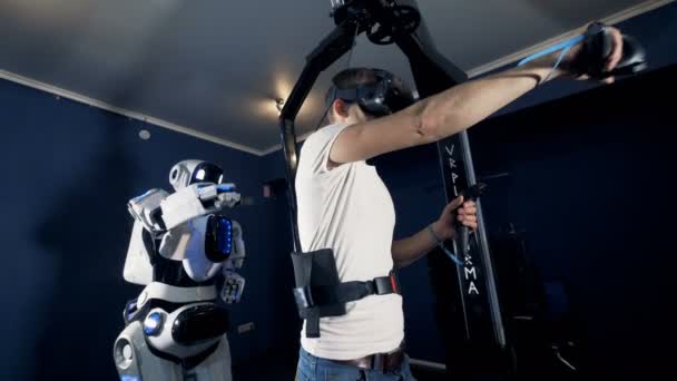 Un joven y un cyborg están moviendo sus manos y cuerpos en sincronía a través de la realidad virtual — Vídeos de Stock