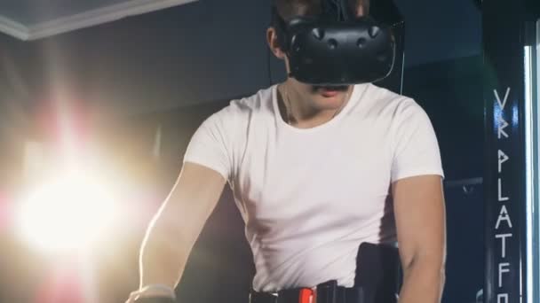 Ein Kerl in vr Brille bewegt sich abseits imaginären Raums vor ihm. Virtual Reality Headset Spiel 360. — Stockvideo