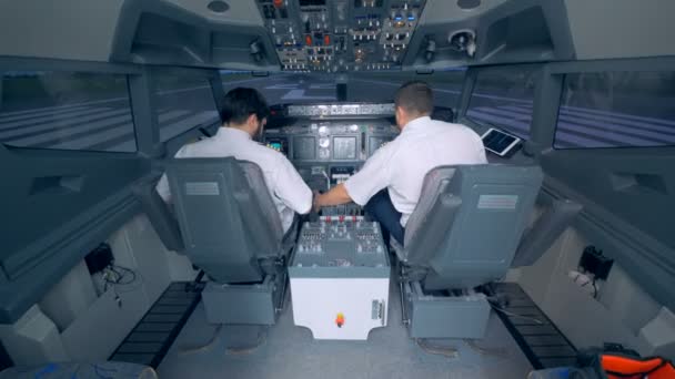 Dos pilotos revisan el equipo en una cabina, vista trasera . — Vídeo de stock