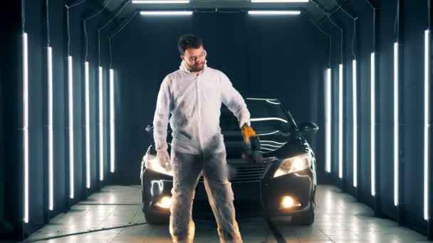 Чоловічий спеціаліст стоячи біля автомобіля з на buffwheel в його руках — стокове відео