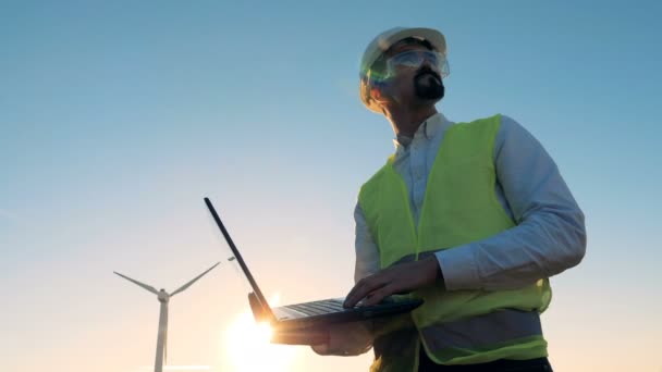 Energetics specialist met een laptop en een windmolen die werken in de buurt van hem. Alternatieve energieconcept. — Stockvideo