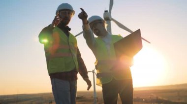 Günbatımı manzara iki mühendis türbini kuleleri bir dizi konuşuyor. Yenilenebilir alternatif enerji, çevre dostu kavramı.