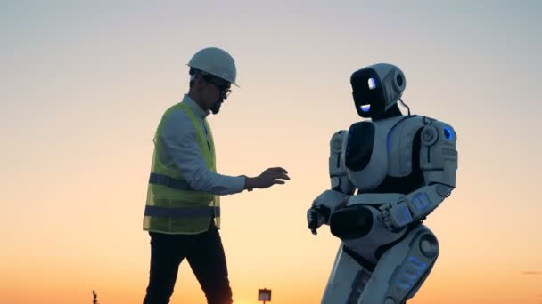 Paisagem do por do sol com um cyborg sendo controlado por um técnico masculino — Vídeo de Stock