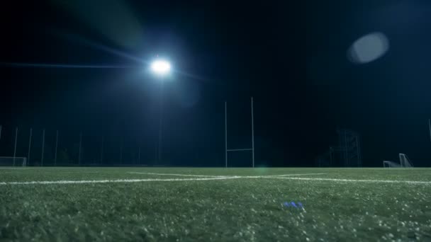 Pelota de fútbol americano está siendo atrapado por un jugador en un campo por la noche — Vídeos de Stock