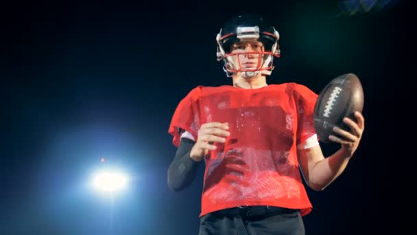 Спортсмен в красной форме готовится бросить мяч для регби — стоковое видео
