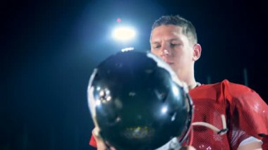 Futbolcu bir Amerikan futbolu arenada olurken onun kask koyuyor