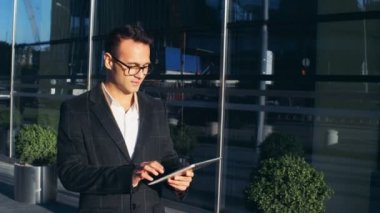 Bir adam bir tablet ile cadde boyunca yürüyor.