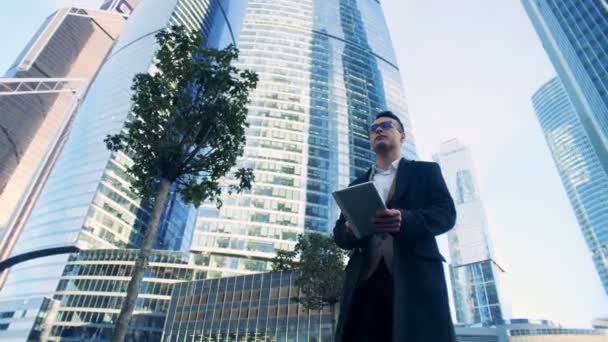 Hombre gerente está caminando a lo largo del complejo de negocios compuesto por rascacielos. Imágenes de la cámara de cine 6K . — Vídeo de stock