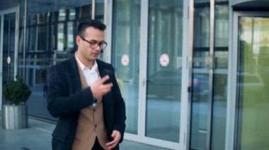 Bir yönetici, başarılı bir iş adamı ofis merkezi yürürken bir telefon görüşmesini yapıyor. Kırmızı epik sinema kamera görüntüleri.