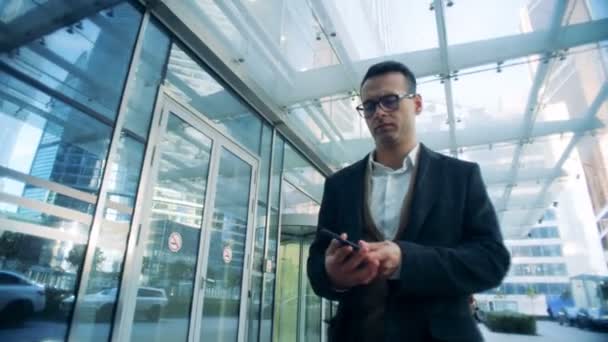 Виконавчий розмовляє по телефону під час прогулянки біля офісної будівлі . — стокове відео