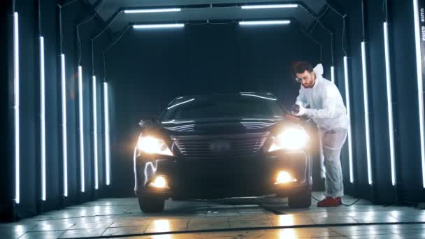 Car workshop with a male worker polishing an automobile — Stock Video