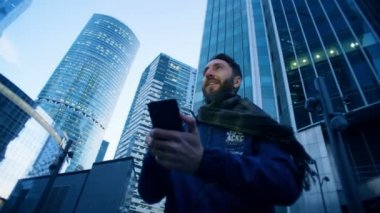 Turist onun smartphone gökdelenler yanında olurken faaliyet göstermektedir. Epik sinema kamera vurdu.