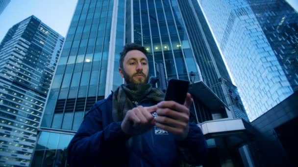 Jeune homme à la mode avec un smartphone est debout au milieu d'un cluster d'affaires. Caméra de cinéma épique prise . — Video