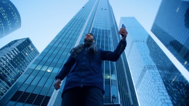 Man glancing around skyscrapers making a videocall. Epic cinema camera shot. — Stock Video